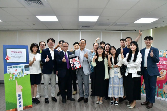 The image shows the President of the Korean Seoul Medical Technologists Association, Bok-Man Kang, leading a team of medical technologists from the Seoul Blood Center's technical department on a visit to the Taipei Blood Donation Center